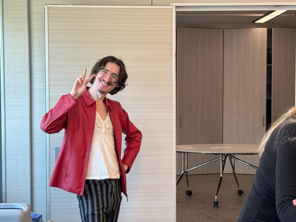 Jeremy Kole in a red jacket with his fingers making a peace sign