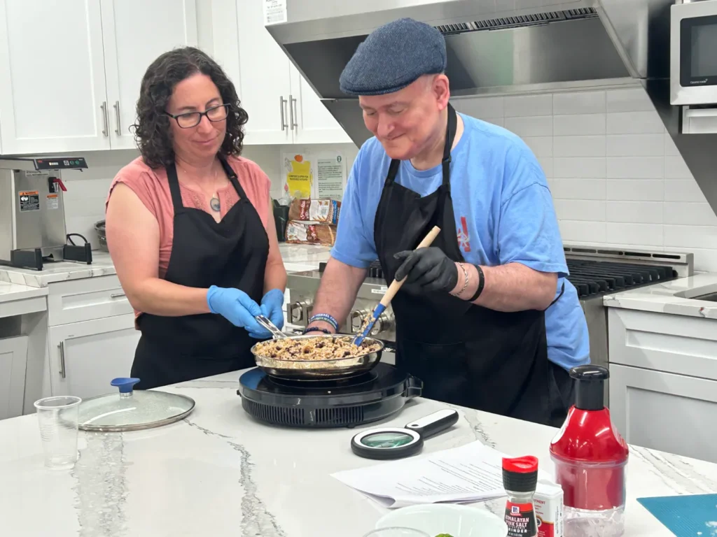 Susan helps a man cook rice and beans with an induction cooktop