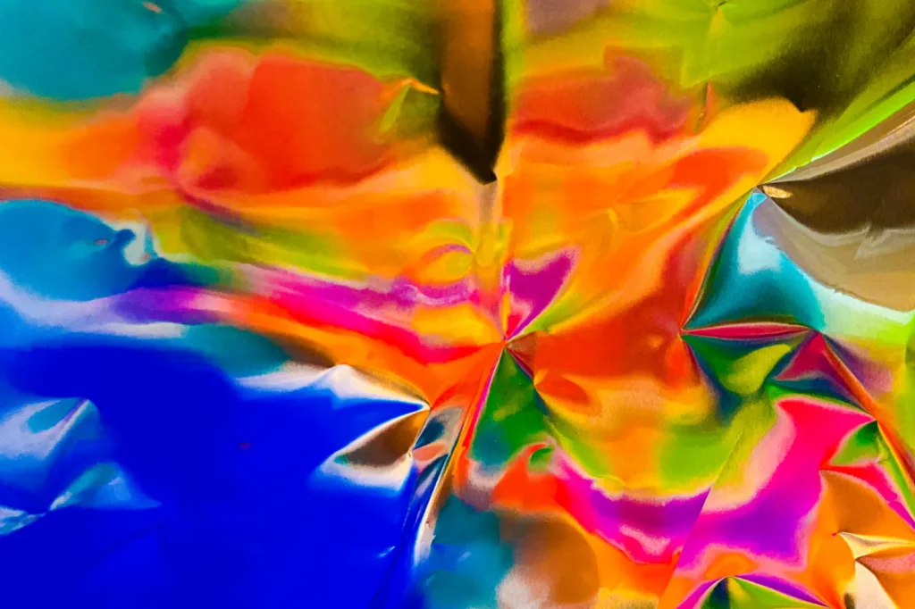 Abstract photo of colorful artwork reflecting off foil. Created by Kari S.